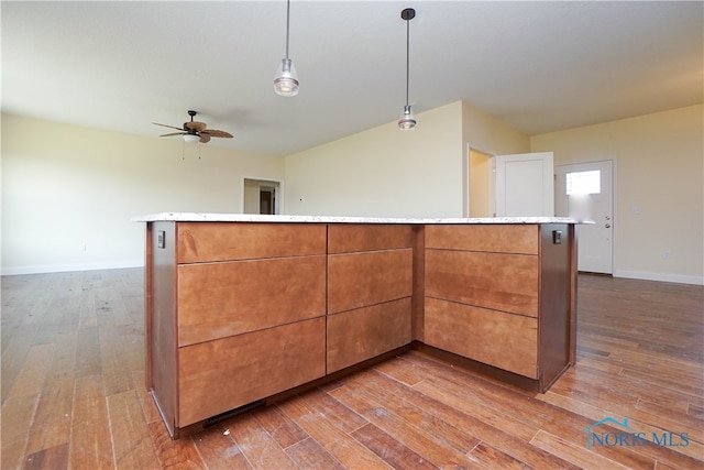 kitchen with decorative light fixtures, hardwood / wood-style floors, ceiling fan, and a center island