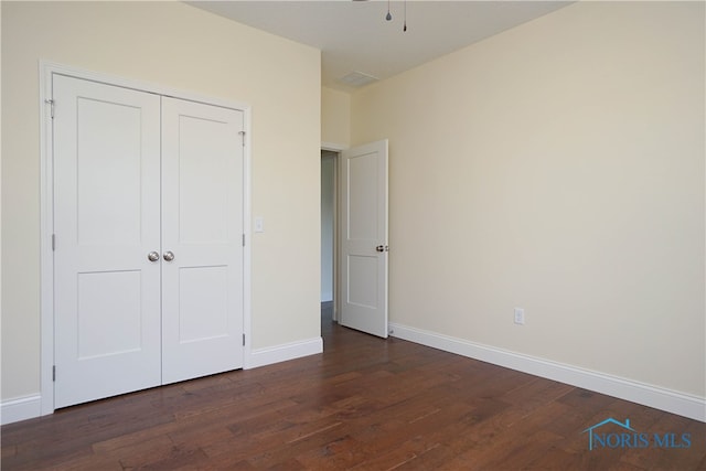 unfurnished bedroom featuring dark wood-type flooring and a closet