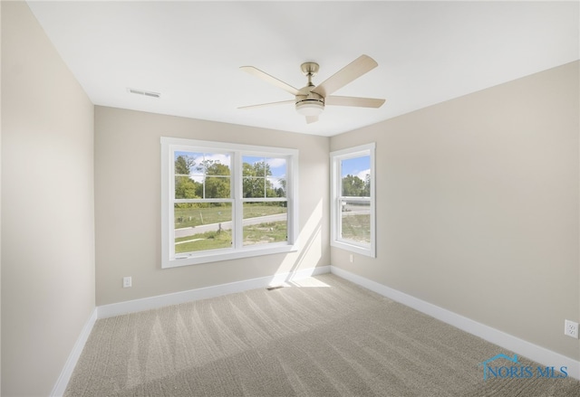 carpeted spare room featuring visible vents, baseboards, and a ceiling fan