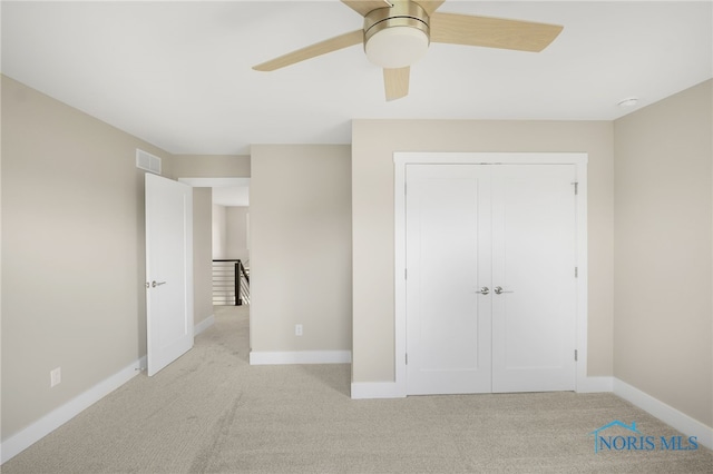 unfurnished bedroom featuring ceiling fan, a closet, and light colored carpet