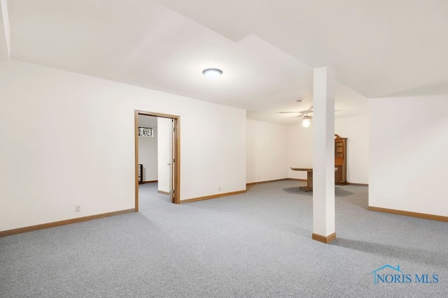 basement with ceiling fan and light colored carpet