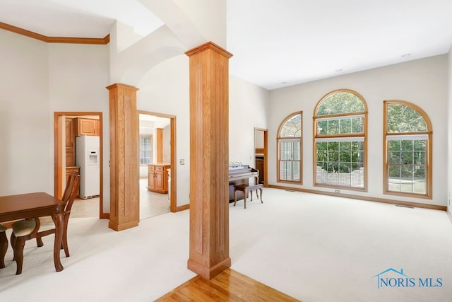 living area with light carpet, ornamental molding, and ornate columns