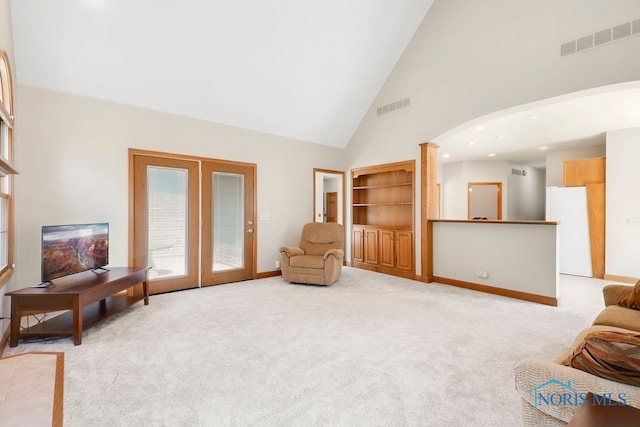 living area featuring high vaulted ceiling, light carpet, and french doors