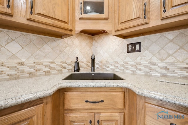 kitchen featuring backsplash, sink, and light stone countertops