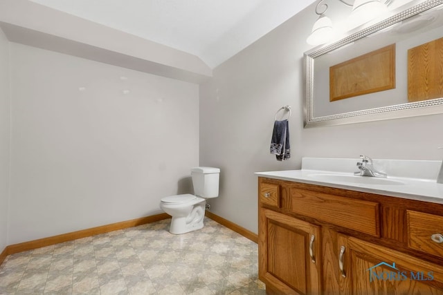 bathroom featuring vanity, toilet, and vaulted ceiling