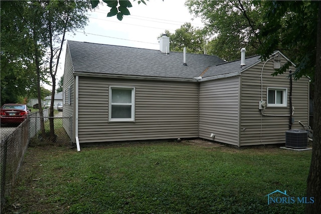 back of house featuring cooling unit and a lawn