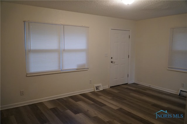 unfurnished room with dark wood-type flooring and a textured ceiling