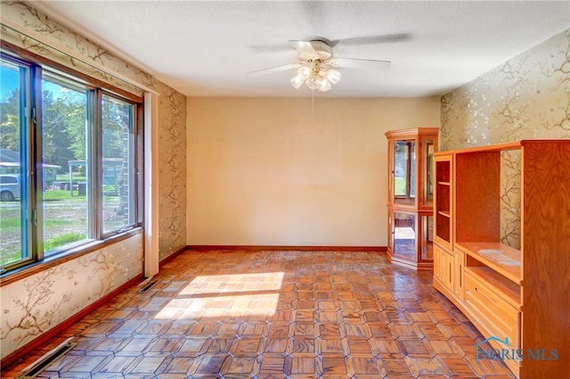 empty room featuring a healthy amount of sunlight and ceiling fan