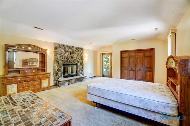 carpeted bedroom featuring vaulted ceiling, a closet, and a fireplace