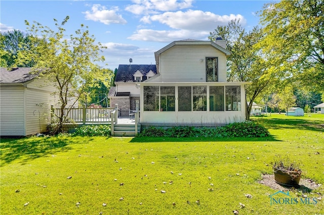 back of house featuring a lawn, a deck, and a sunroom