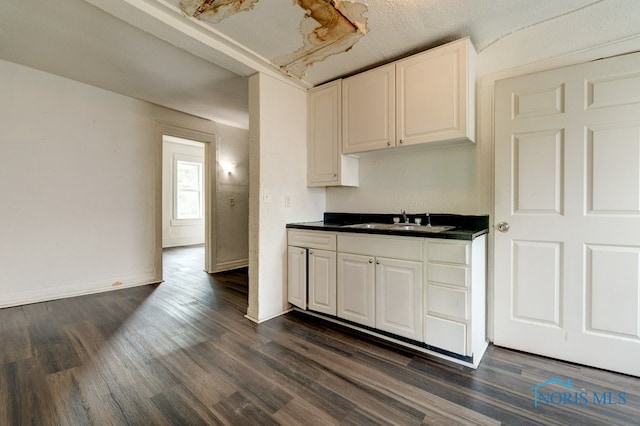 kitchen with white cabinetry, a textured ceiling, dark wood-type flooring, and sink