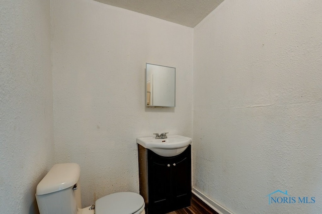 bathroom featuring a textured ceiling, hardwood / wood-style floors, vanity, and toilet