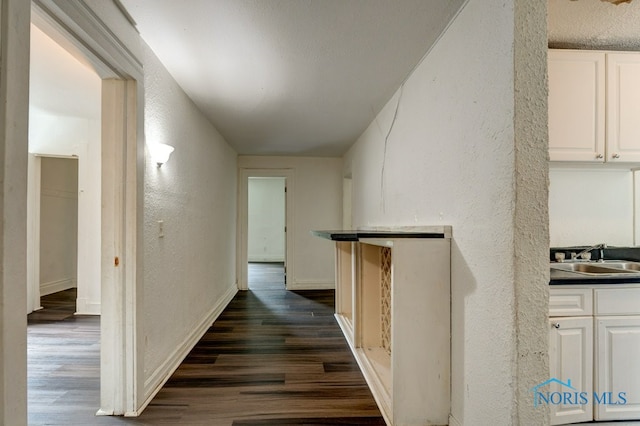 corridor featuring dark wood-type flooring and sink