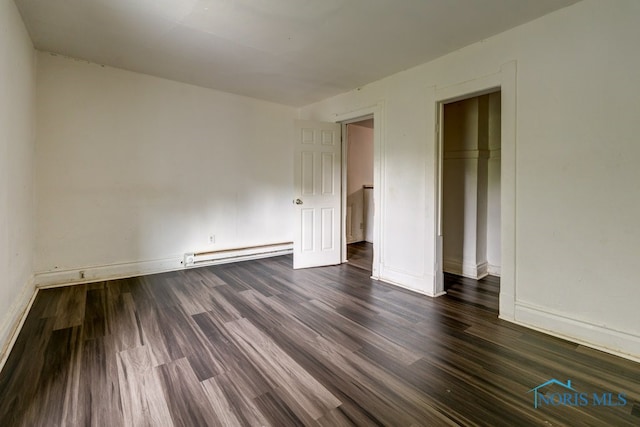 unfurnished room with baseboard heating and dark wood-type flooring