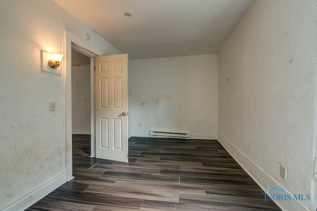 spare room with dark hardwood / wood-style floors and a baseboard radiator