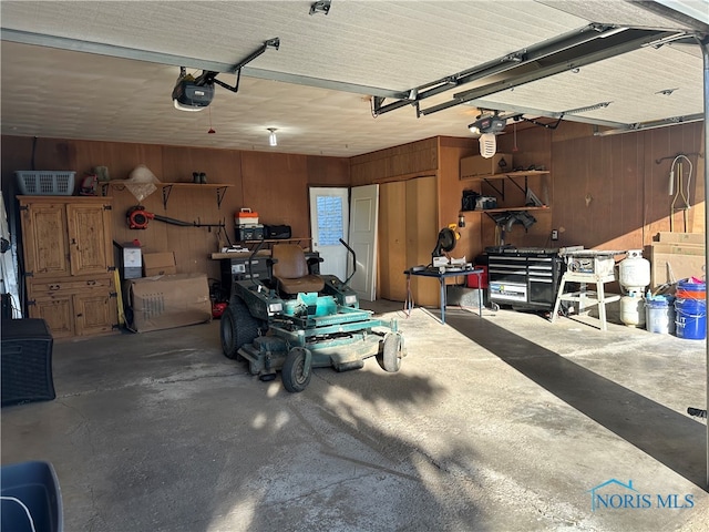 garage with a garage door opener, wood walls, and a workshop area