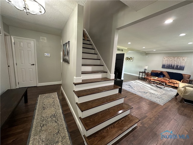 staircase with wood-type flooring and a textured ceiling