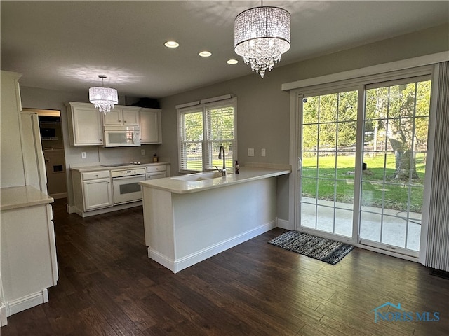 kitchen featuring an inviting chandelier, hanging light fixtures, kitchen peninsula, and white appliances