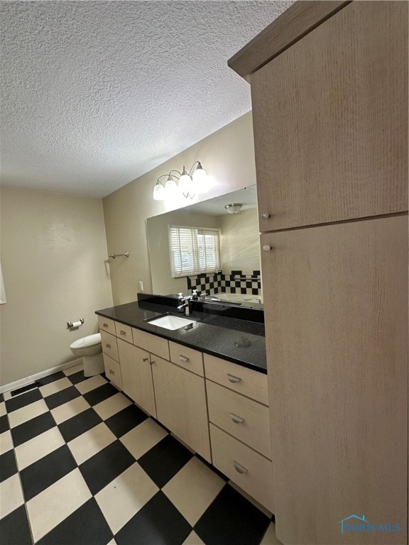 bathroom with vanity, toilet, a textured ceiling, and tasteful backsplash