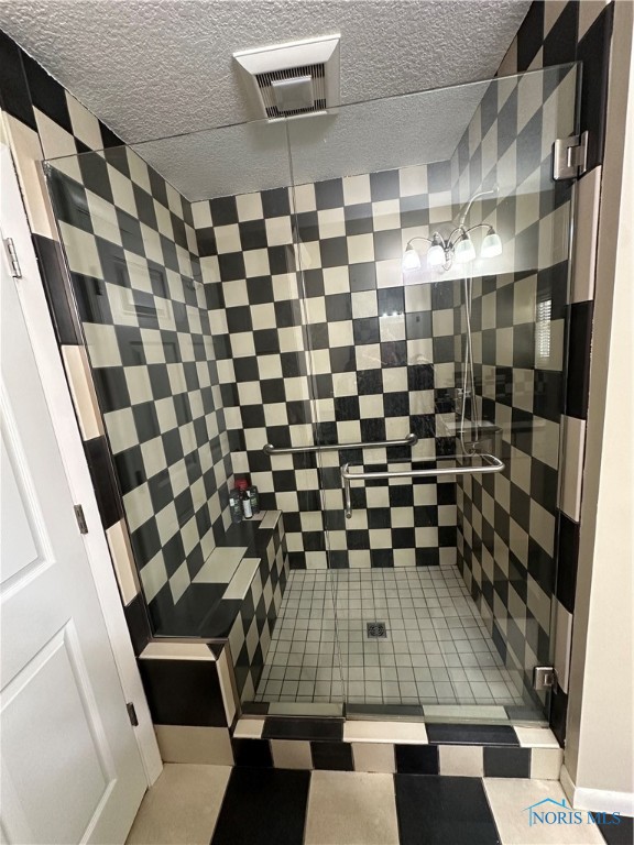 bathroom featuring a textured ceiling and tiled shower