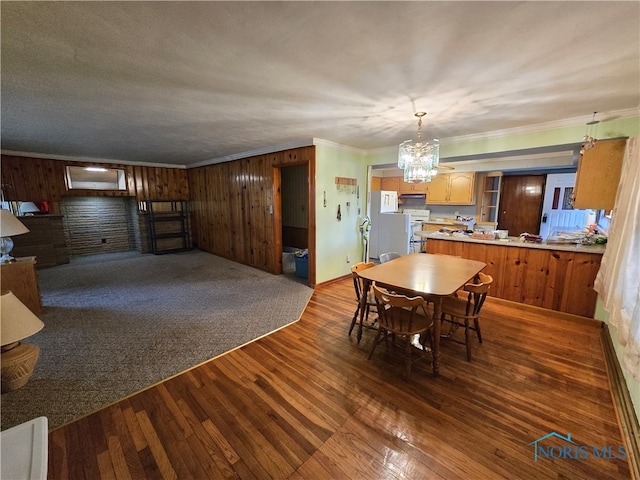 dining space featuring ornamental molding, a textured ceiling, a notable chandelier, dark hardwood / wood-style flooring, and wood walls