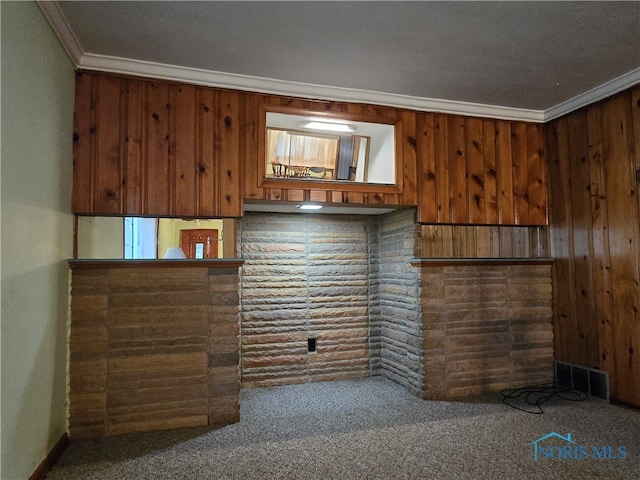 carpeted empty room featuring ornamental molding and wooden walls