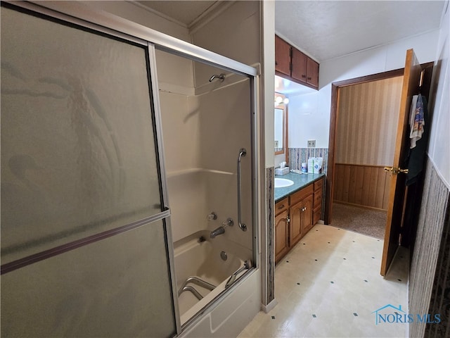 bathroom featuring vanity, wooden walls, and shower / bath combination with glass door