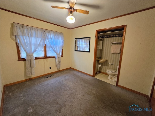 unfurnished bedroom featuring ornamental molding, ceiling fan, carpet, connected bathroom, and a closet