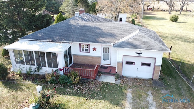 view of front of home with a garage, a front yard, and a sunroom