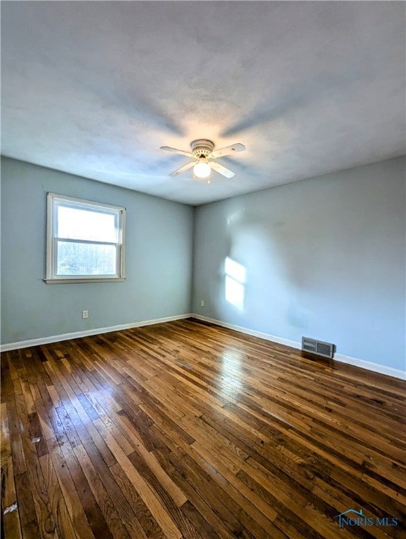 empty room featuring dark wood-type flooring and ceiling fan