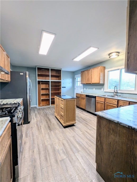 kitchen with appliances with stainless steel finishes, sink, a kitchen island, and light hardwood / wood-style floors