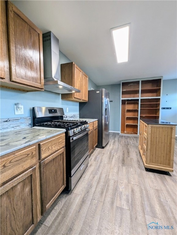 kitchen featuring light stone countertops, light hardwood / wood-style floors, stainless steel appliances, and wall chimney range hood