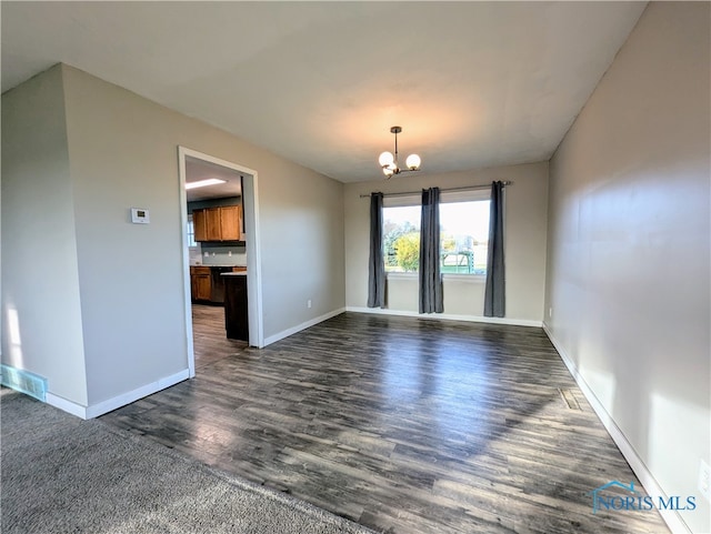 empty room featuring a chandelier and dark hardwood / wood-style floors