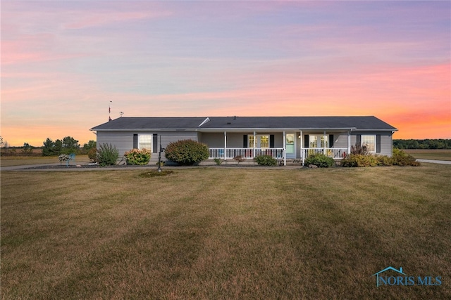 ranch-style home featuring a yard and covered porch