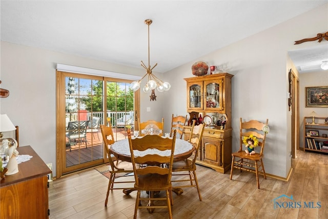 dining room with lofted ceiling, light hardwood / wood-style flooring, and a notable chandelier