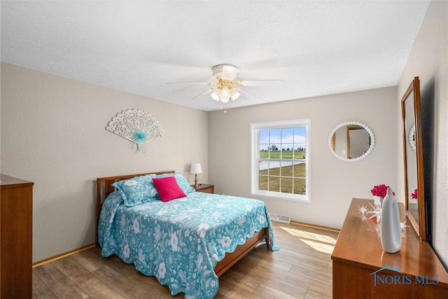 bedroom with a textured ceiling, hardwood / wood-style flooring, and ceiling fan