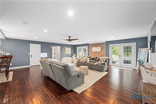 living room with a brick fireplace, dark wood-type flooring, ceiling fan, and french doors