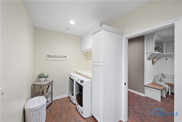 clothes washing area with cabinets and washing machine and clothes dryer