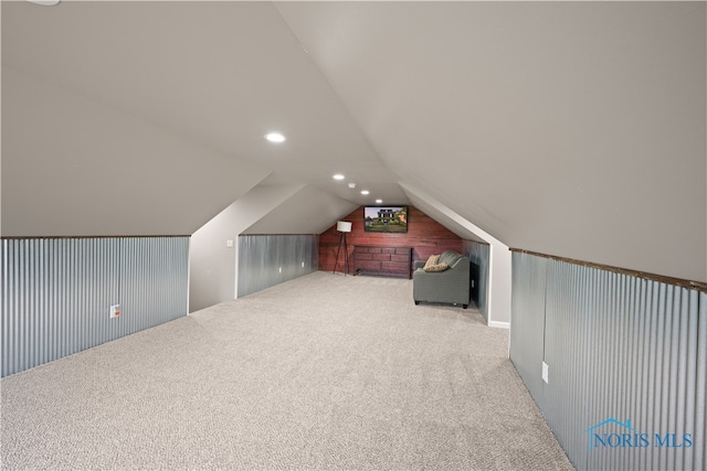 additional living space with wooden walls, carpet, and vaulted ceiling