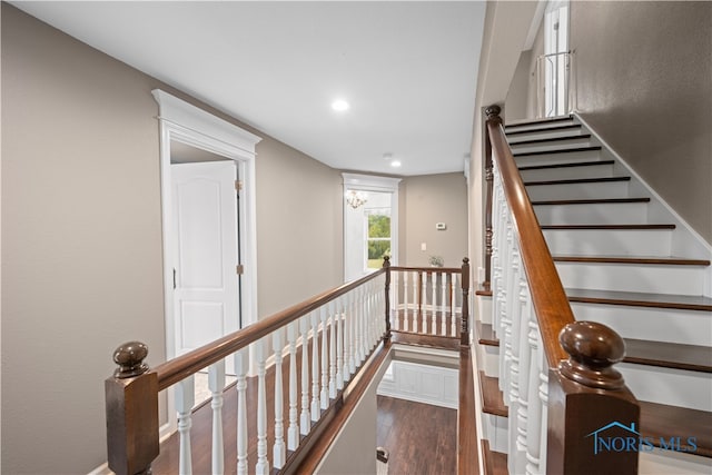 stairs featuring wood-type flooring and an inviting chandelier