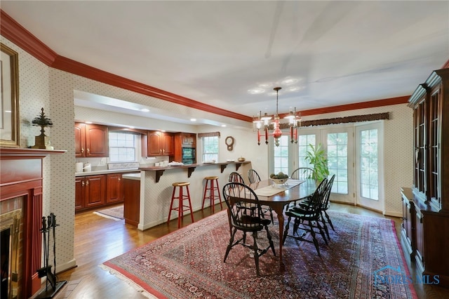 dining area featuring ornamental molding, light wood-type flooring, a chandelier, and french doors