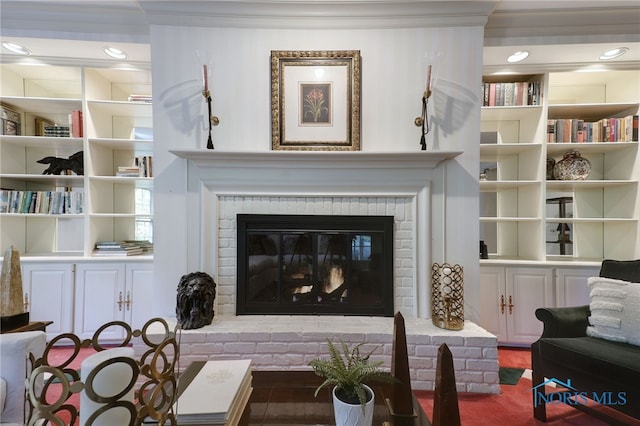 living room with built in shelves, a fireplace, and ornamental molding