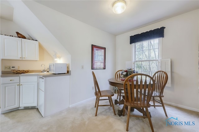 dining area with vaulted ceiling and light colored carpet