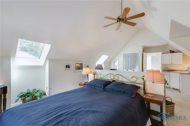 bedroom with lofted ceiling with skylight, sink, ceiling fan, and light colored carpet