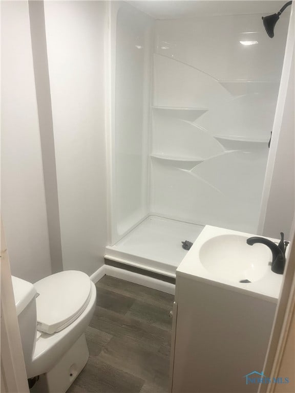 bathroom featuring vanity, a shower, hardwood / wood-style floors, and toilet