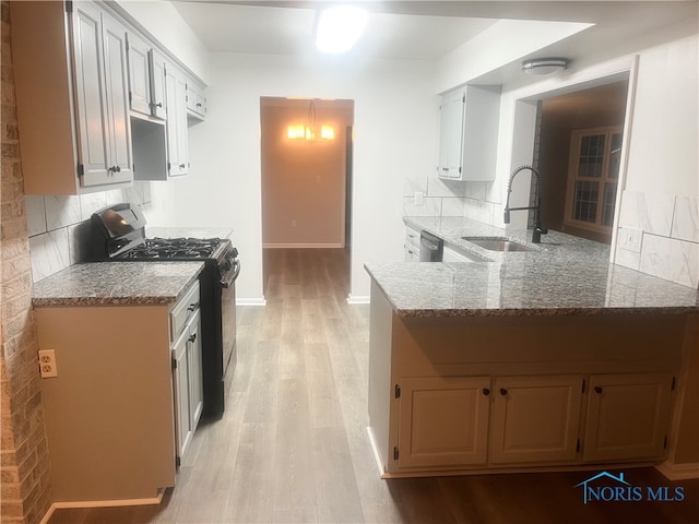 kitchen featuring kitchen peninsula, sink, white cabinets, and black gas range