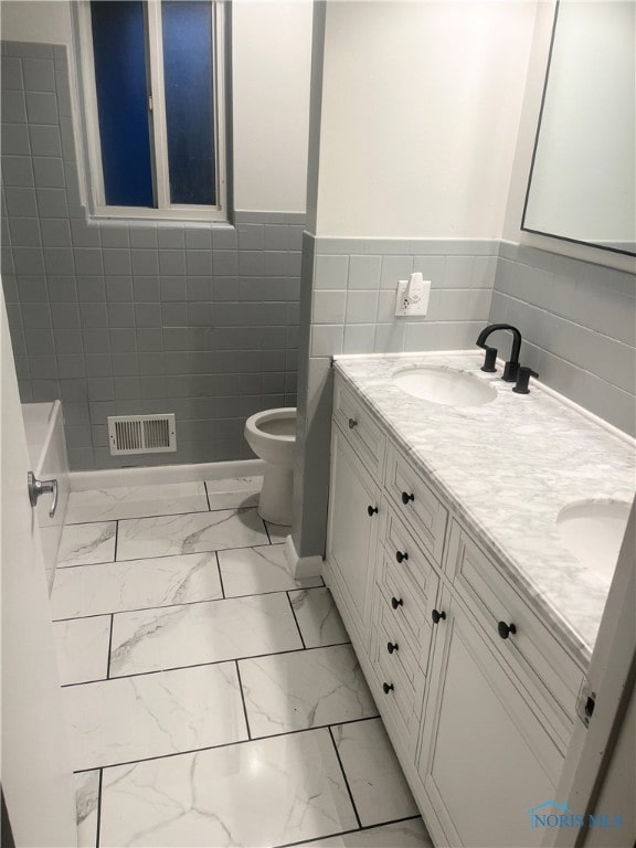 bathroom with vanity, tile walls, and toilet