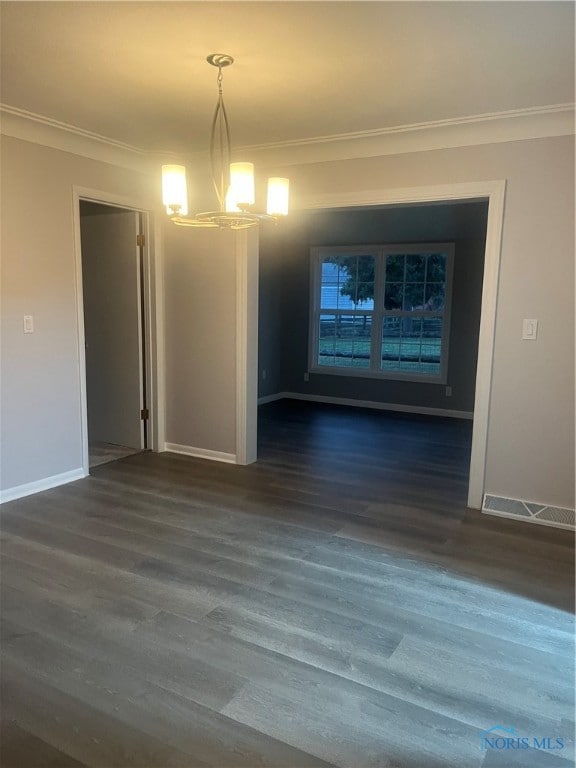 empty room with crown molding, dark hardwood / wood-style floors, and a notable chandelier