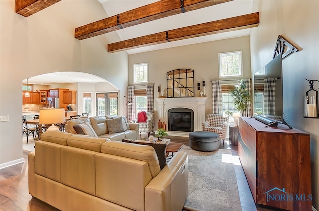 living room featuring hardwood / wood-style floors, beam ceiling, and a high ceiling