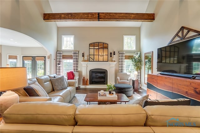 living room featuring plenty of natural light, a towering ceiling, and beamed ceiling